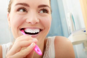 Young woman brushing cleaning teeth. Girl with toothbrush in bathroom. Oral hygiene.